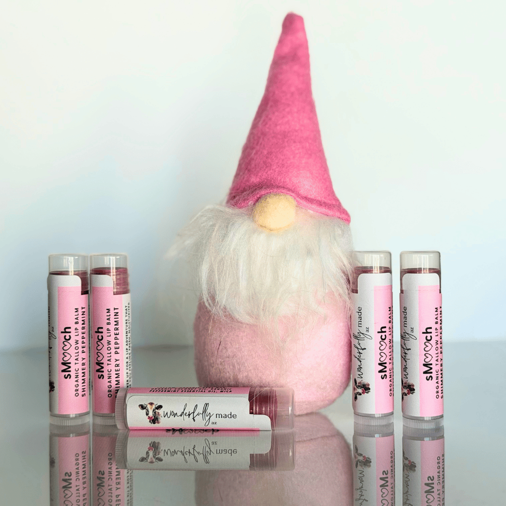 Pink gnome with Smooch lip balm products on a reflective surface
