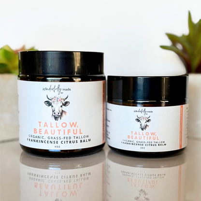 Two jars of 'Tallow Beautiful' Frankincense Citrus balm on a reflective surface with a blurred background