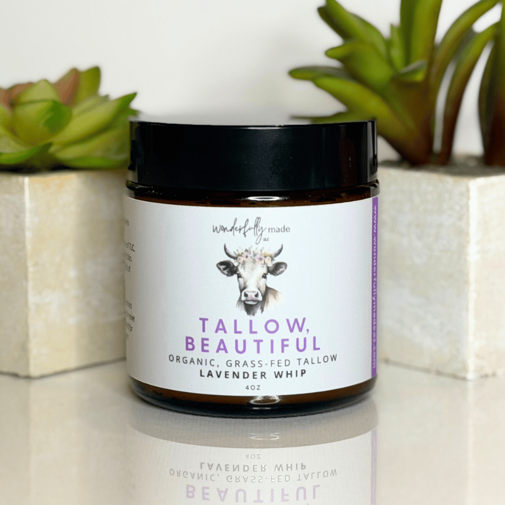 Jar of 'Tallow Beautiful' product with a cow illustration on a white surface with plants in the background