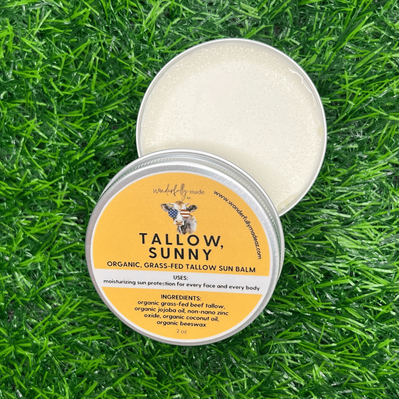 Tallow Sunny Sun Balm with open tin lid on grass