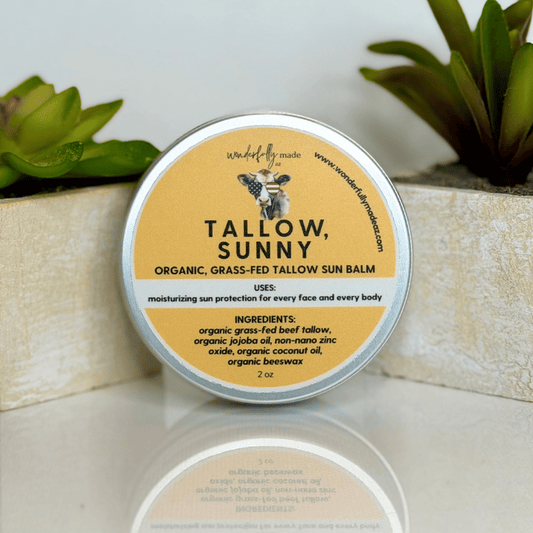 Tallow, Sunny organic sun balm tin with a plant in the background