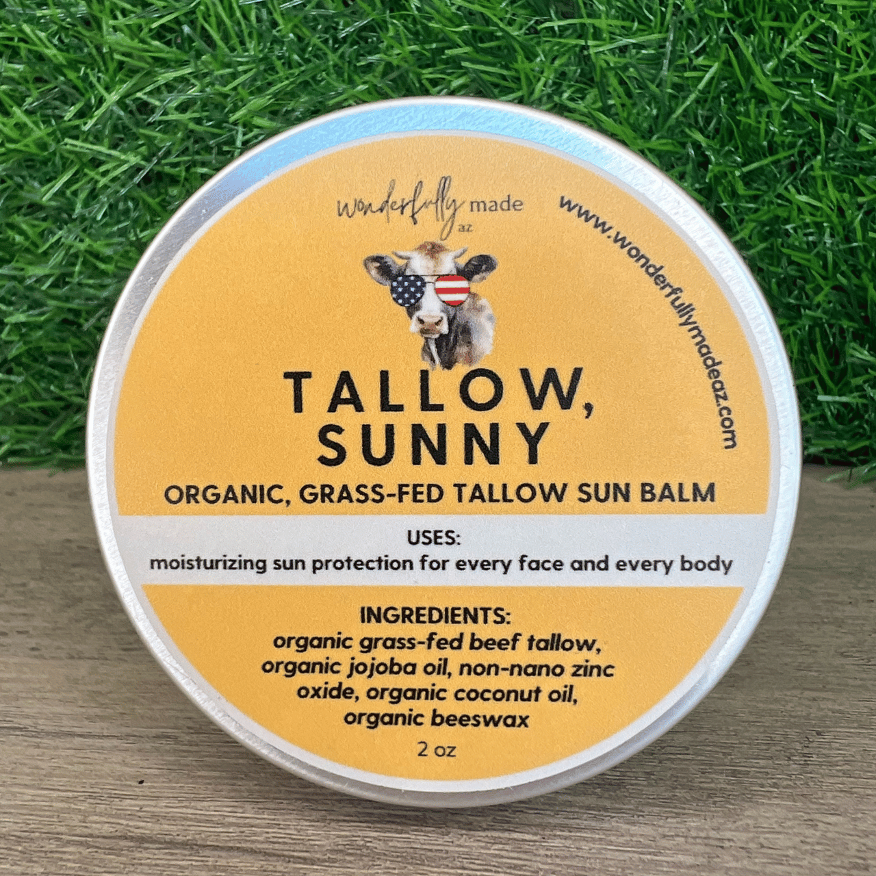Organic Tallow Sunny sun balm with grass background on wood surface
